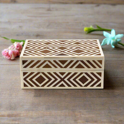 Modern geometric bone inlay jewelry box in brown and ivory finish displayed in a contemporary bedroom setting.