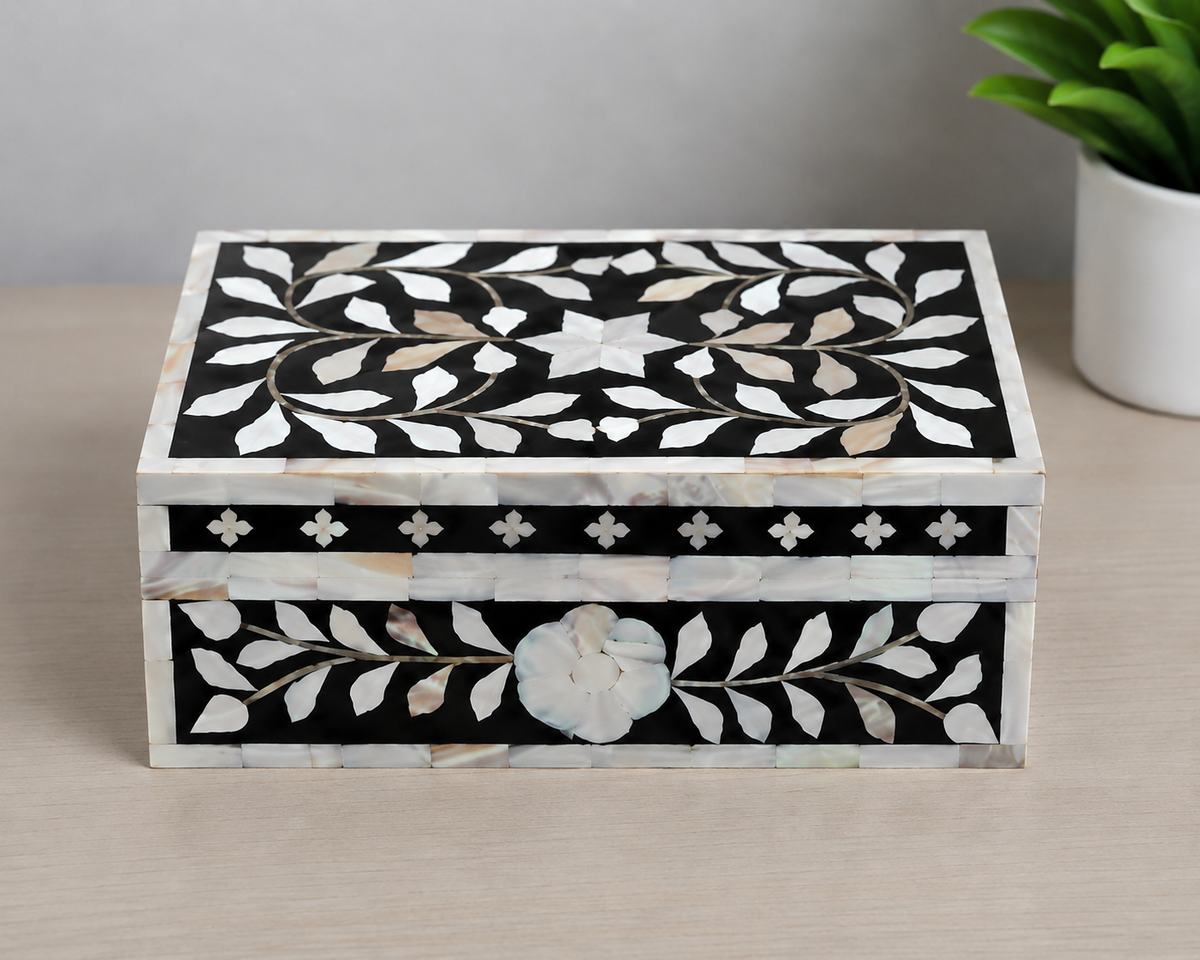Close-up view of handcrafted mother of pearl floral inlay detailing on black jewelry box.