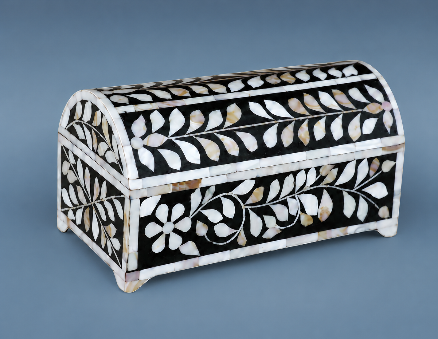 Open Mother of Pearl inlay jewelry box with floral design holding jewelry on a marble vanity
