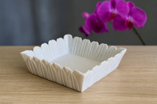 Hand-carved white marble flower-shaped bowl used as a decorative fruit or centerpiece dish.
